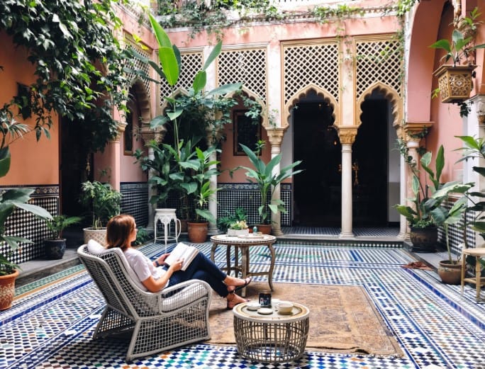 Mulher sozinha a relaxar num pátio de riad tradicional em Marraquexe